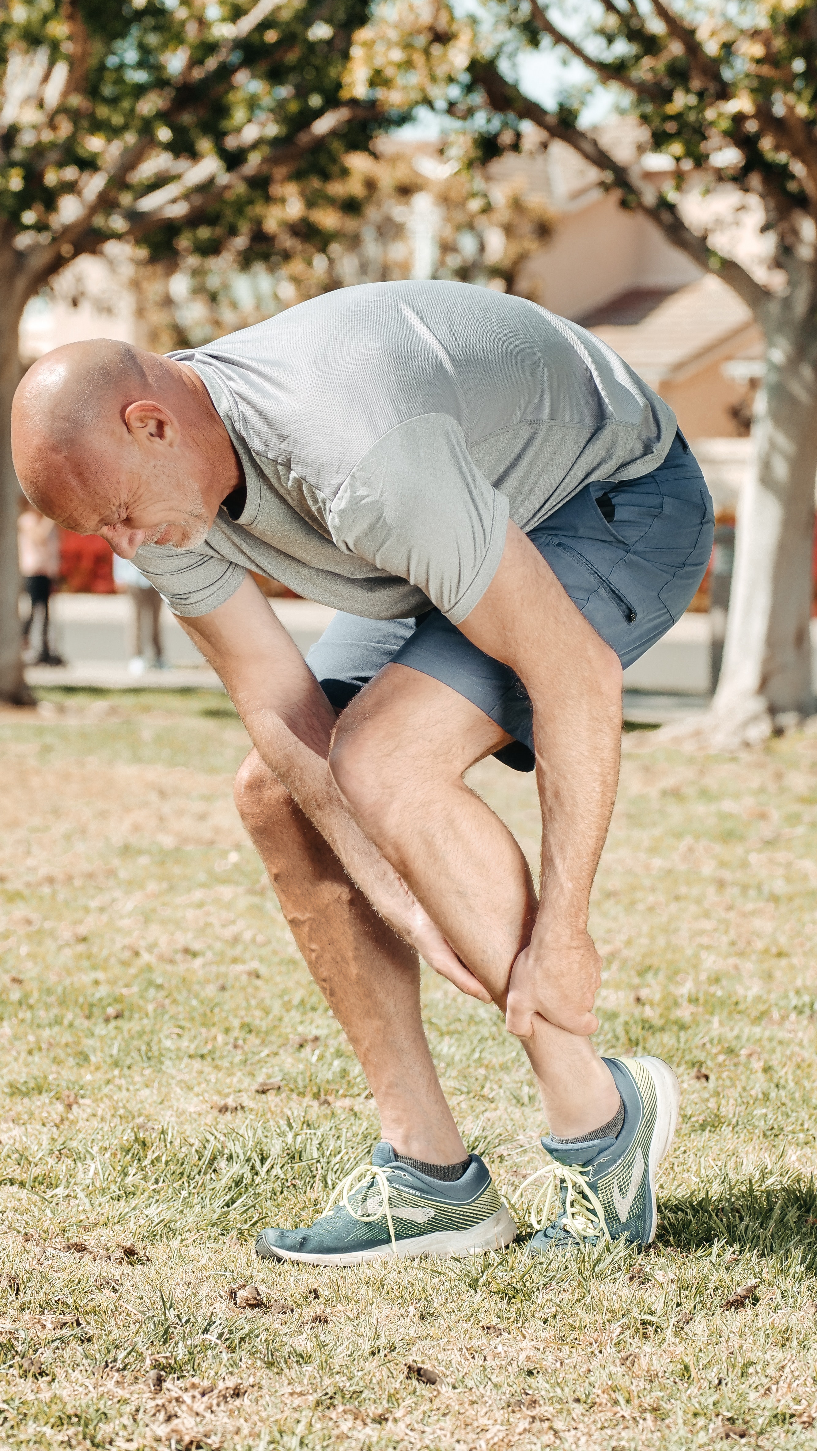 Foto de um atleta com a mão na perna, com cara de dor.