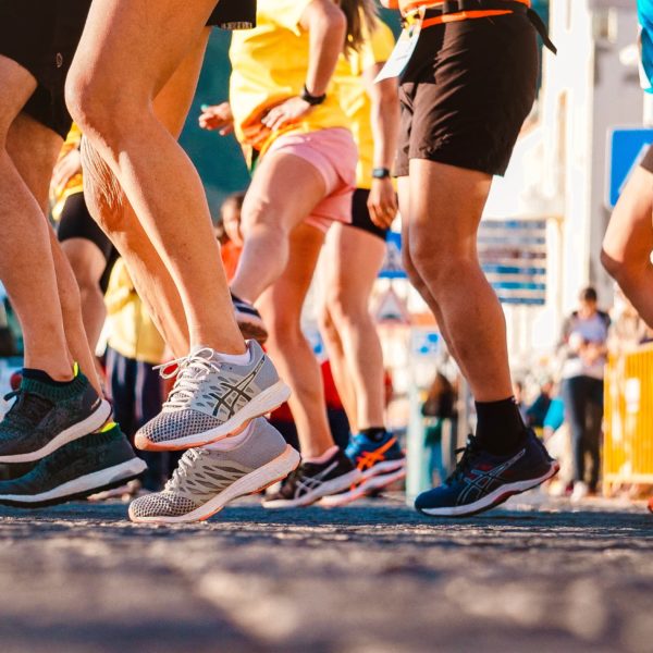 Diversos tênis de corridas e pernas. Na largada de uma corrida